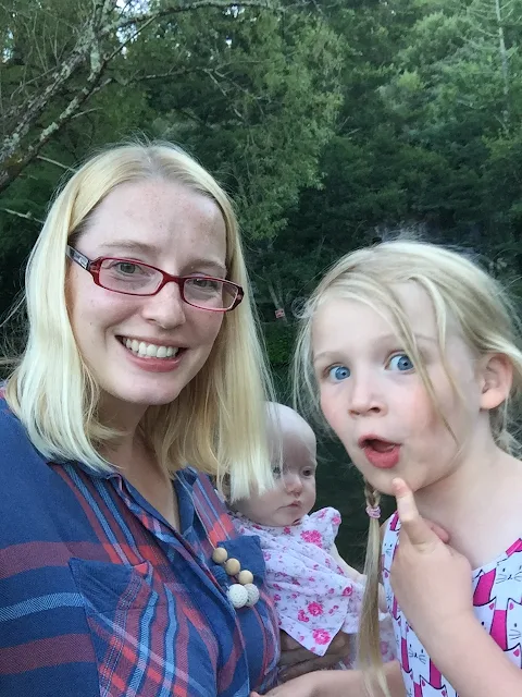 A mother, a baby and a big sister pulling a silly face