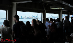  Travellers and commuters line the railings of the Staten Island Ferry for a view of the city skyline on the return trip to Manhattan. Travel photography by Kent Johnson.
