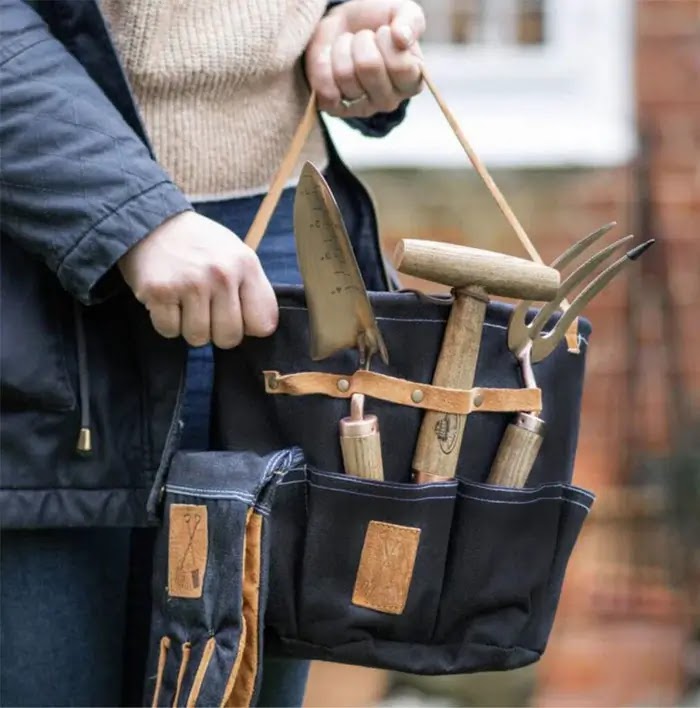 Woman holding denim garden bag with hand tools