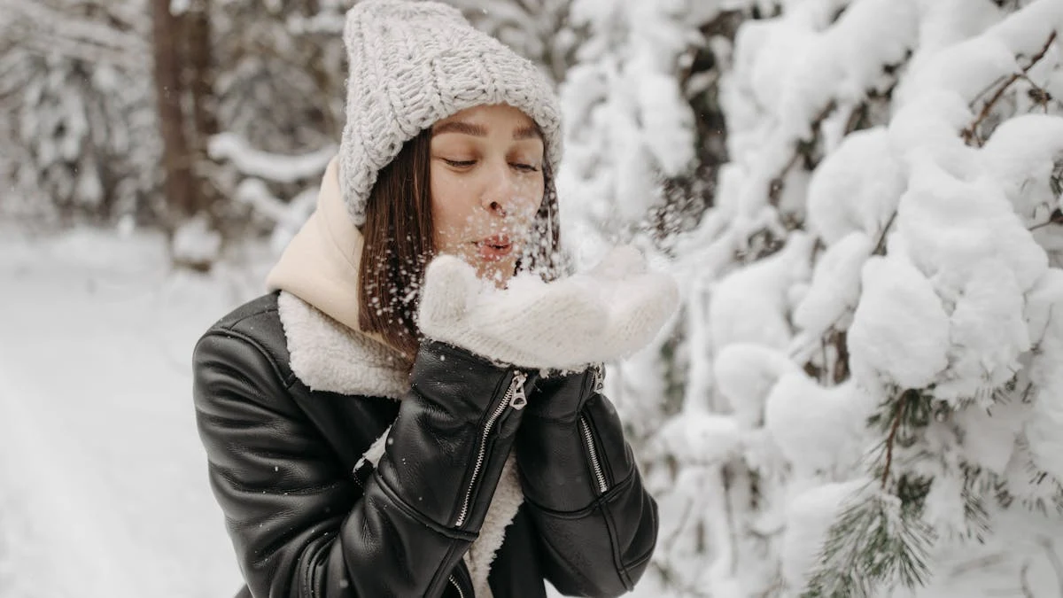 Woman in a Black Leather Jacket Blowing Snow on Her Hands