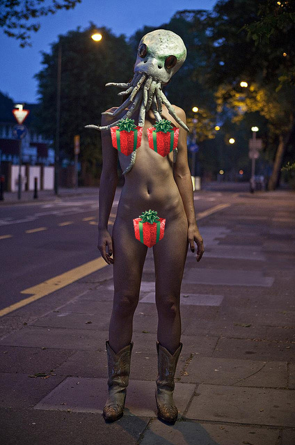 Artistic photo of a naked girl wearing a Cthulhu mask on the street at night