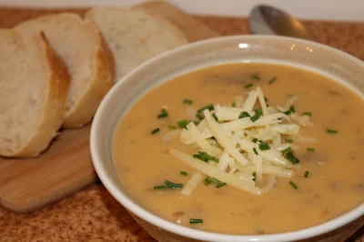 Bowl of baked potato soup with sliced bread.