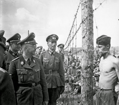 Himmler, acompañado de soldados frente a un prisionero en el campo de concentración nazi