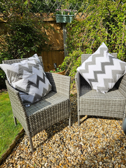 Two rattan outdoor chairs with large chevron grey and white cushions