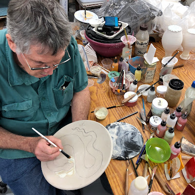 Bruce is glazing a plate with one of his snake images using a latex technique