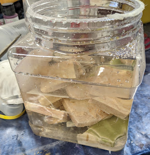 Plastic jar full of marble pieces, tiles, and sugar water