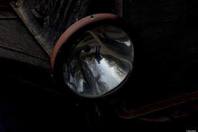 A reflection of myself in the headlight of an old and rusty car. Silverado, California - 2018. © Evan's Studio