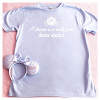 The Liberty Bell Boutique lilac A dream is a wish your heart makes T Shirt, in white writing and with white Cinderella carriage silhouette above.