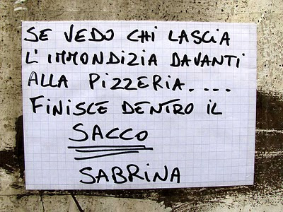 Sign: trash in front of a pizzeria