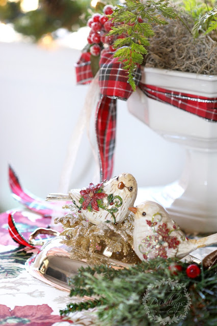 Christmas birds sitting on a silver tray with greenery and berries.