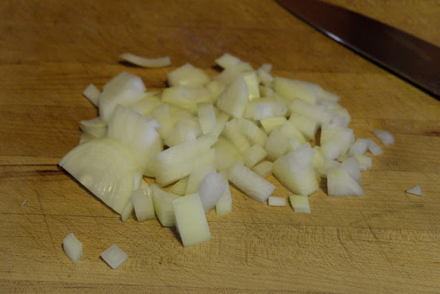 An onion diced on a cutting board.