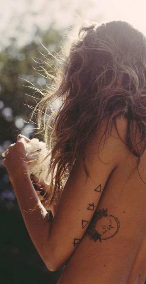 Chica hippie con tatuaje de cuatro triangulos en el brazo