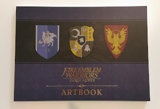 photo of the artbook with the three house emblems on the cover