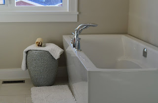 White simple bathtub with towel on basket beside it