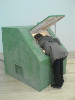 Kim looks down the hatch of a green bunker,which is about 5' tall and 5' square.  There's a light and ladder inside and the use of mirrors tricks you into thinking the ladder goes down for ever...