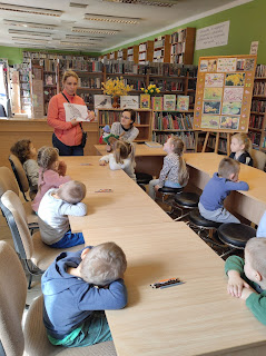 Pani przedszkolanka pokazuje przedszkolakom obrazek wróbla. Tło: sala biblioteczna.