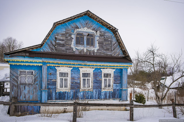Двухэтажное деревянное синее здание с белыми наличниками