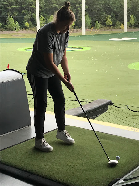Elizabeth getting ready to hit the ball at Top Golf