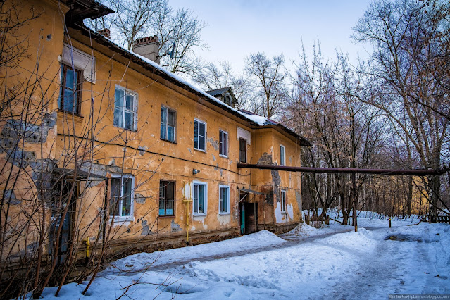 Старое двухэтажное здание с трубой теплотрассы