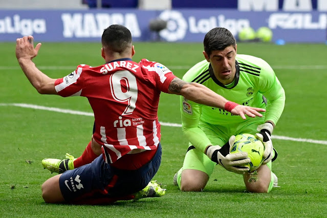 Real Madrid goal keeper Thiabut Courtois stops Atletico Madrid forward Luis Suarez