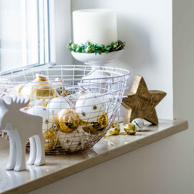 Deko an Weihnachten. Goldene Kugeln, Metallglöckchen, Rentier auf Fensterbank