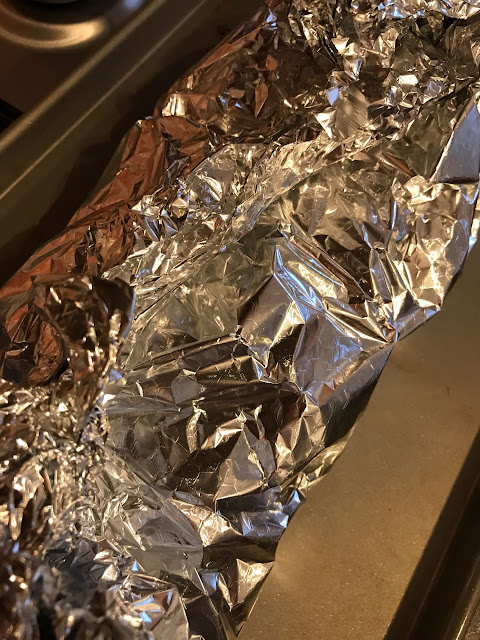 Bread wrapped in foil and on a baking tray