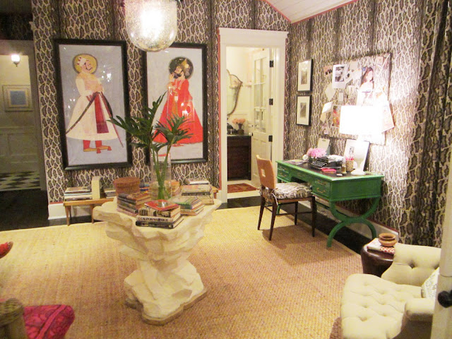 Alternative view of the sitting room in the Windsor house with Peter Dunham's animal print Gattapardo linen fabric on the walls and matching floor length curtains, on the walls are two paintings in black frames, a lacquered green desk, dark wood floor, a rockery inspired center table and a sea grass rug