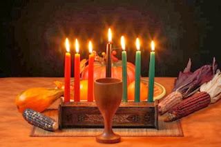 Photo of the symbols of Kwanzaa, a cup, a menorah, and dried ears of corn.