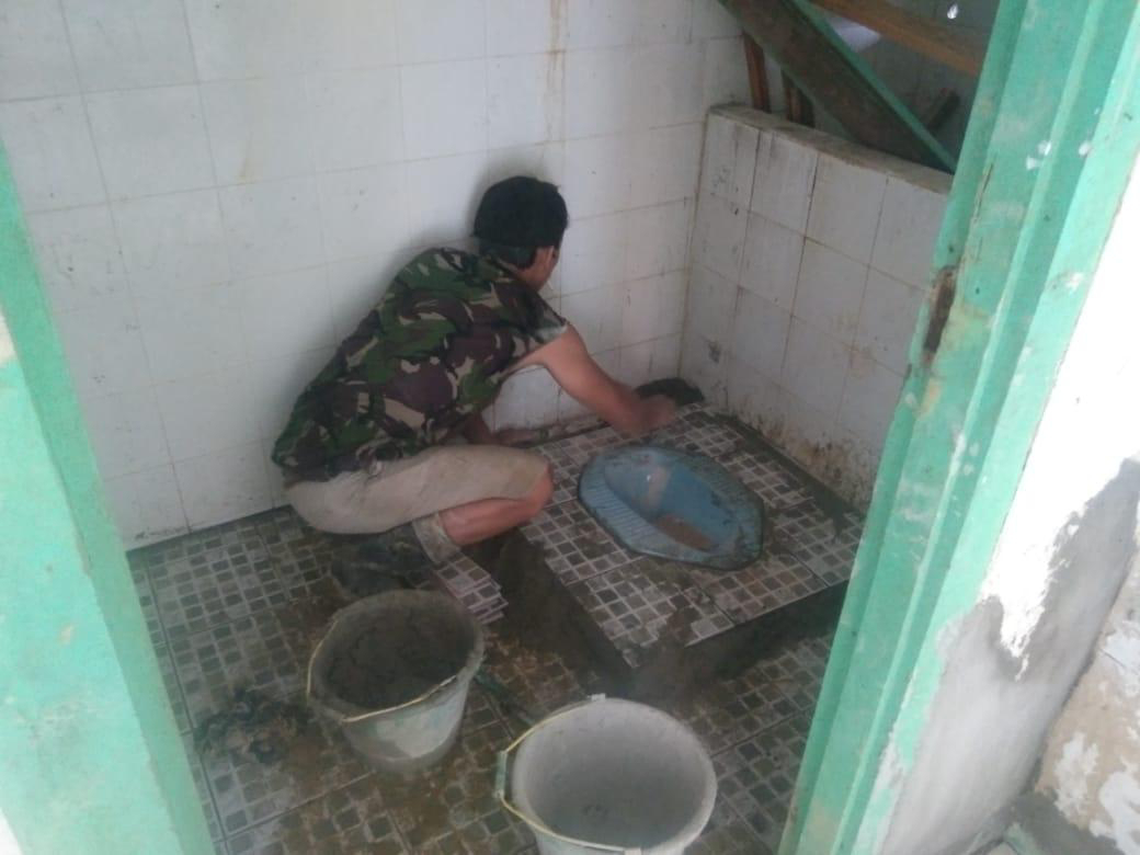 Anggota satgas TMMD Ke 111 memasang tegel keramik lantai di WC Puskesmas Pembantu
