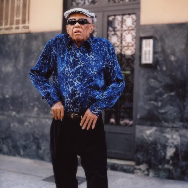 Um homem parece ajeitar o cinto da calça em uma rua.