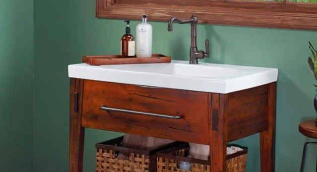 A rustic wood vanity by Ronbow stands out in this sage green bathroom.
