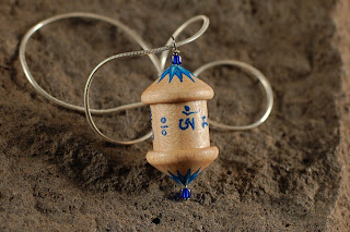 A WOODEN PRAYER WHEEL PENDANT