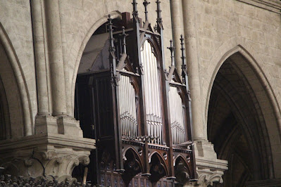 Stone gothic arches in a church plus a wood case with organ pipes