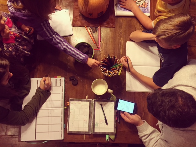 Family gathered around the table planning out their week Mormon Mom Planner