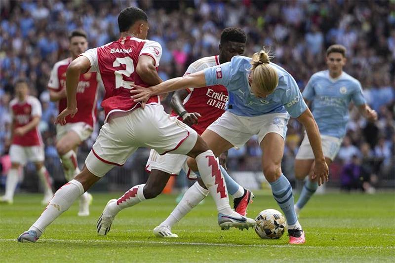 Arsenal s William Saliba, left, challenges for the ball with Manchester City s Erling Haaland