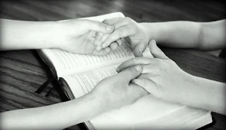 duas pessoas de mãos dadas em cima de uma bíblia