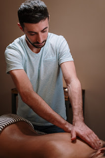 A person lying on a massage table, receiving a full body massage from a professional therapist. The therapist is using various techniques to manipulate the muscles and soft tissues of the body. The person looks relaxed and at ease, with a peaceful expression on their face.