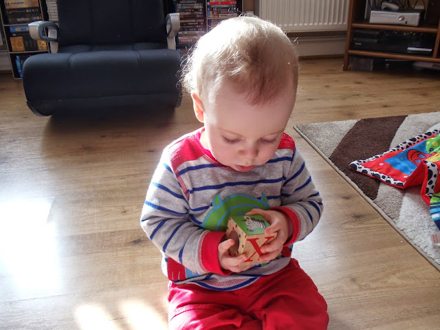 little boy sat up playing with  wooden blocks