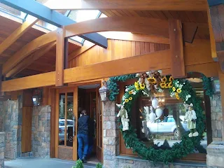 Entrada a edificio de piedra y madera en Gramado decorado con una guirnalda de pino y flores