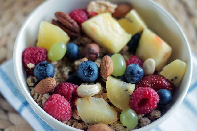 bowl of fruit with berries, nuts and pineapple