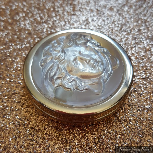 transparent domed medusa head on lid of gold eyeshadow pot