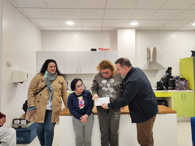 Cuatro personas posando en una entrega de un donativo