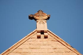 cross at the top of a peaked roof on a church