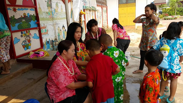 niños ofreciendo guirnaldas y el agua a sus maestras