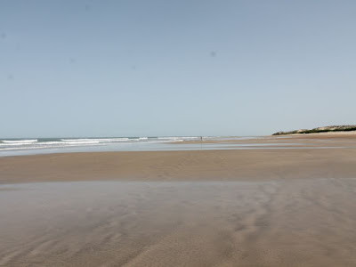 breiter, menschenleerer Strand, links das Meer.