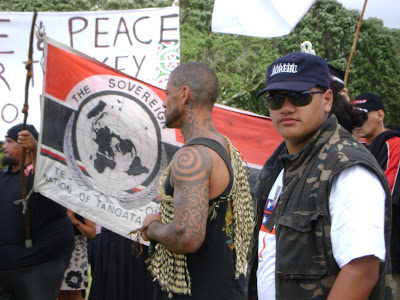  female ta moko on her chin, holding a traditional wooden staff with Paua 