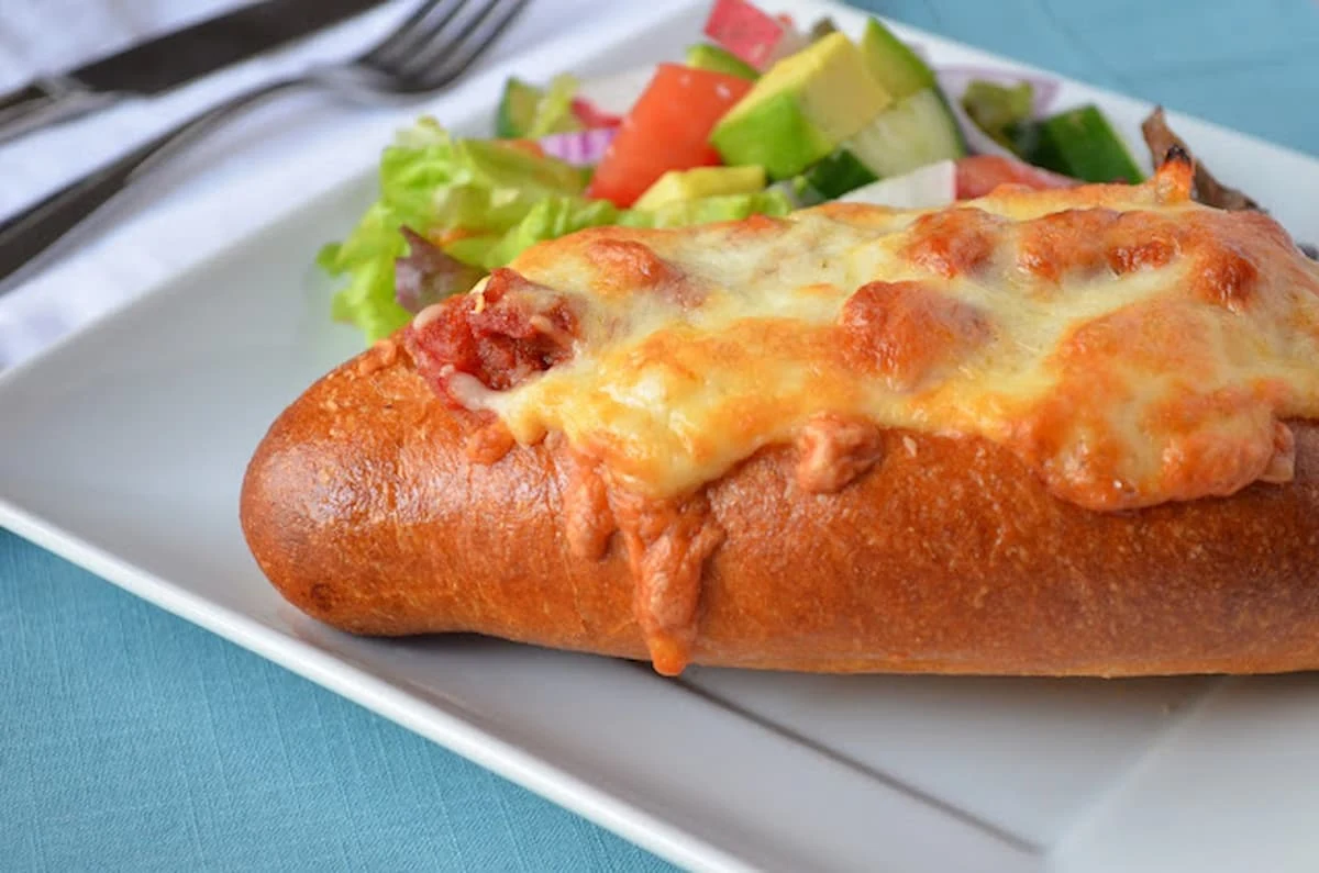 Baked Meatball Subs on a hoagie roll on a white plate on top of a light blue placemat.