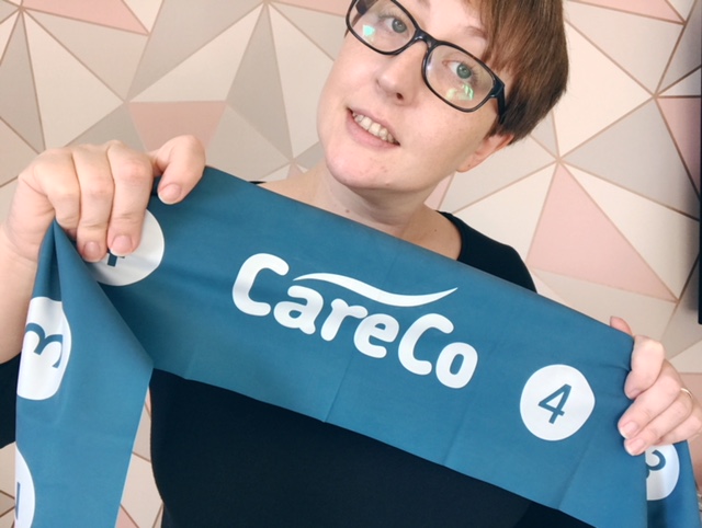 A woman holding up a resistance band with CareCo written on it