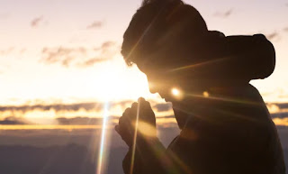 Hombre orando en puesta de sol