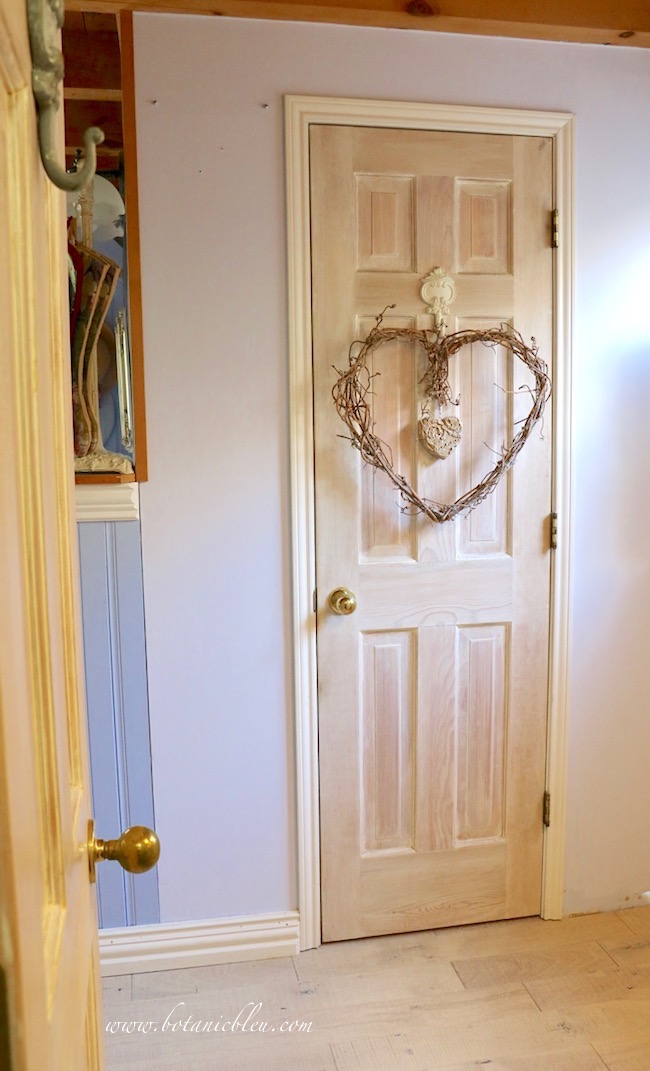 A simple heart-shaped grapevine wreath hangs on a closet door